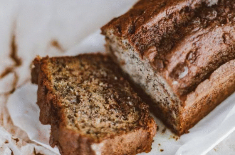 Moist Greek Yogurt Banana Bread sliced on a white serving plate, showing a soft and fluffy texture, photographed in a bright modern kitchen with clean white and beige tones.